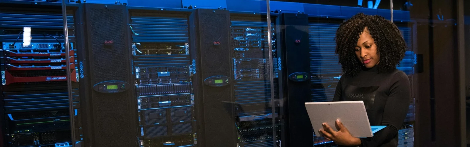 Eine IT-Spezialistin arbeitet mit einem Laptop vor modernen Servern im Rechenzentrum.